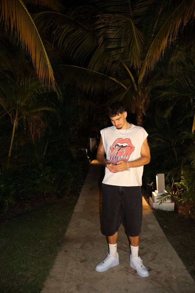Ben Shtolzberg in a graphic sleeveless tee and shorts under palm trees at night