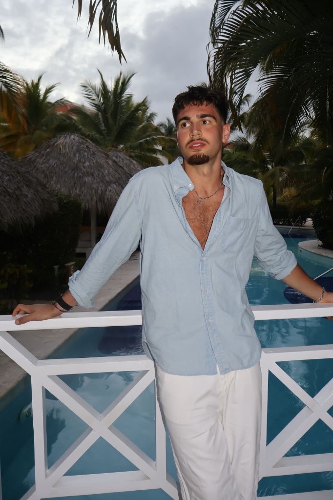 Ben Shtolzberg in a light linen shirt by a resort pool with palm trees